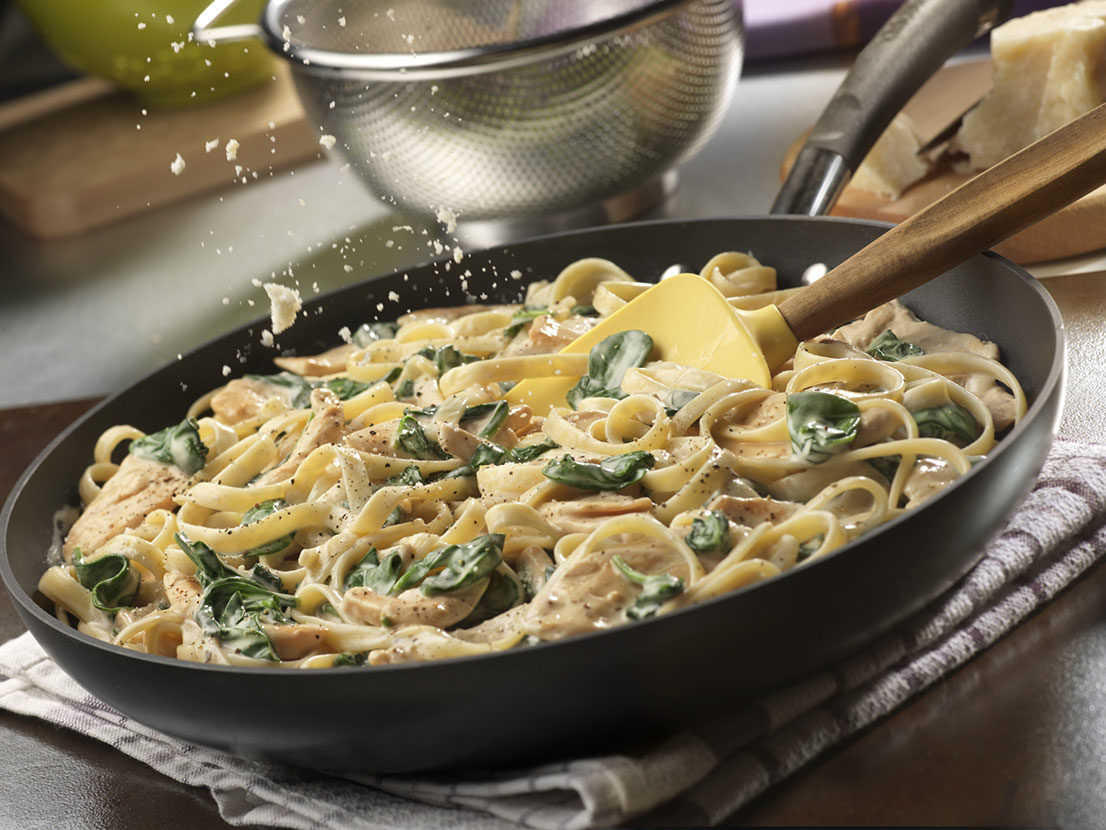 Simple Chicken Spinach Alfredo with Fettuccine with Prego® sauce cooking in a frying pan