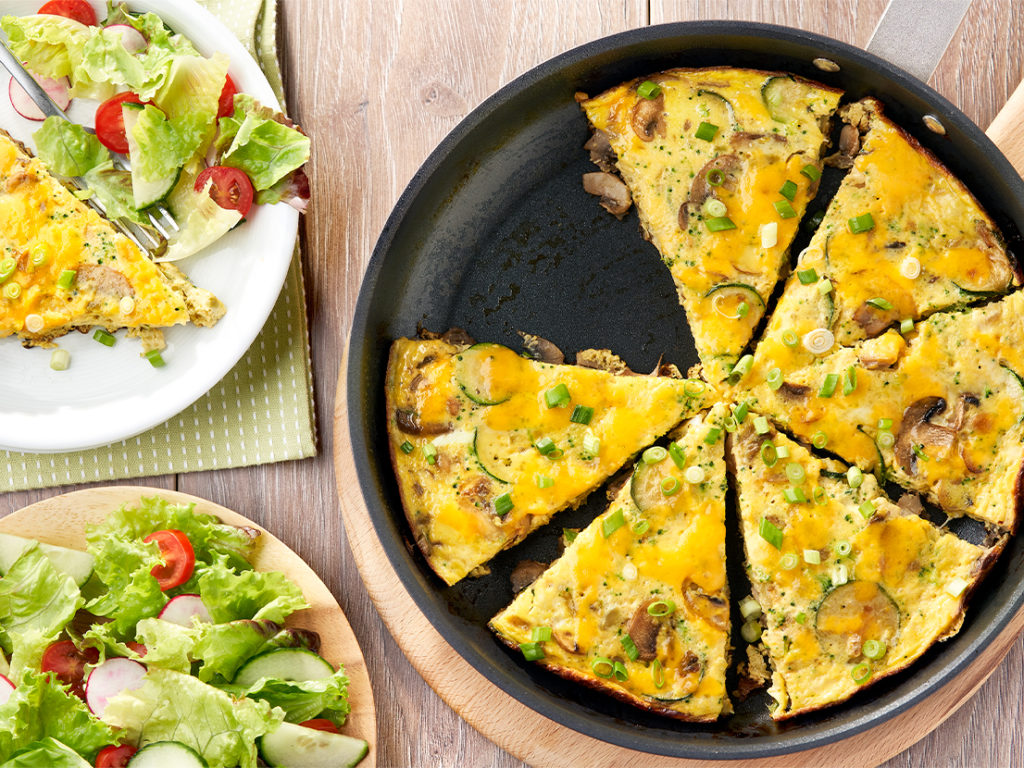 An image of prepared Cheddar Broccoli Frittata made with eggs, Campbell's® Condensed Broccoli Cheese Soup, mushrooms, yellow onion, zucchini, Cheddar cheese and green onion.